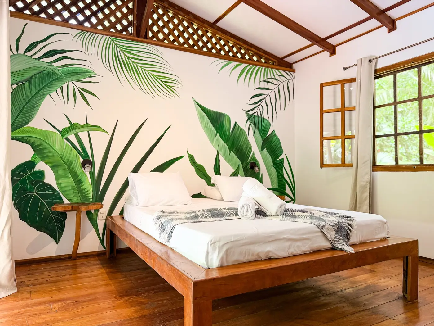 Bright bedroom with queen-size bed and hand-painted botanical wall